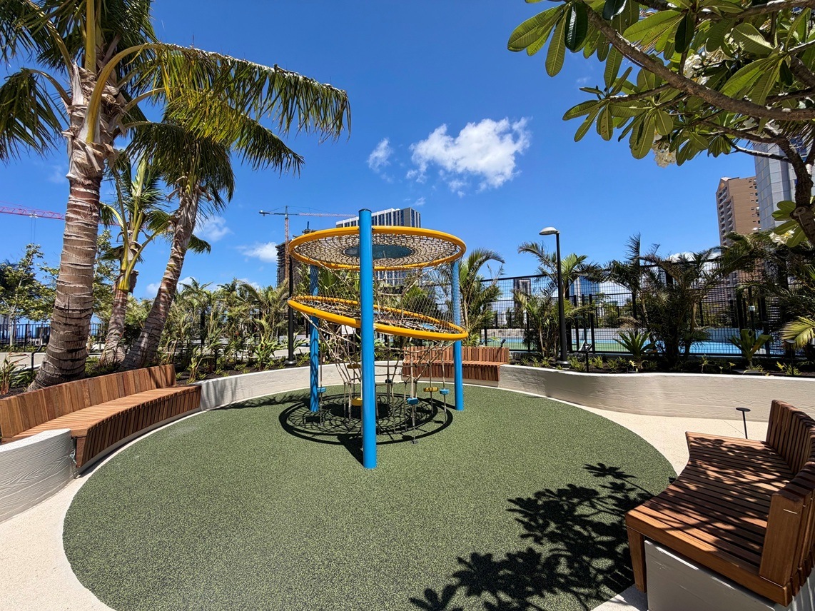 A playground with a blue and yellow structure and a green lawn.